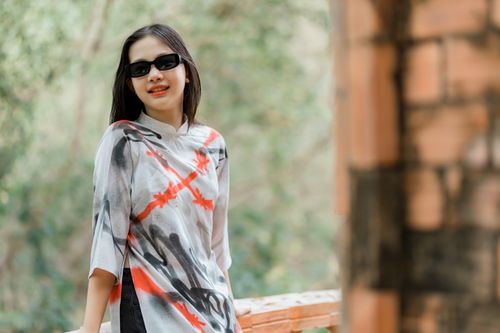 Free A fashionable woman in sunglasses and a patterned top enjoying a sunny day outdoors. Stock Photo