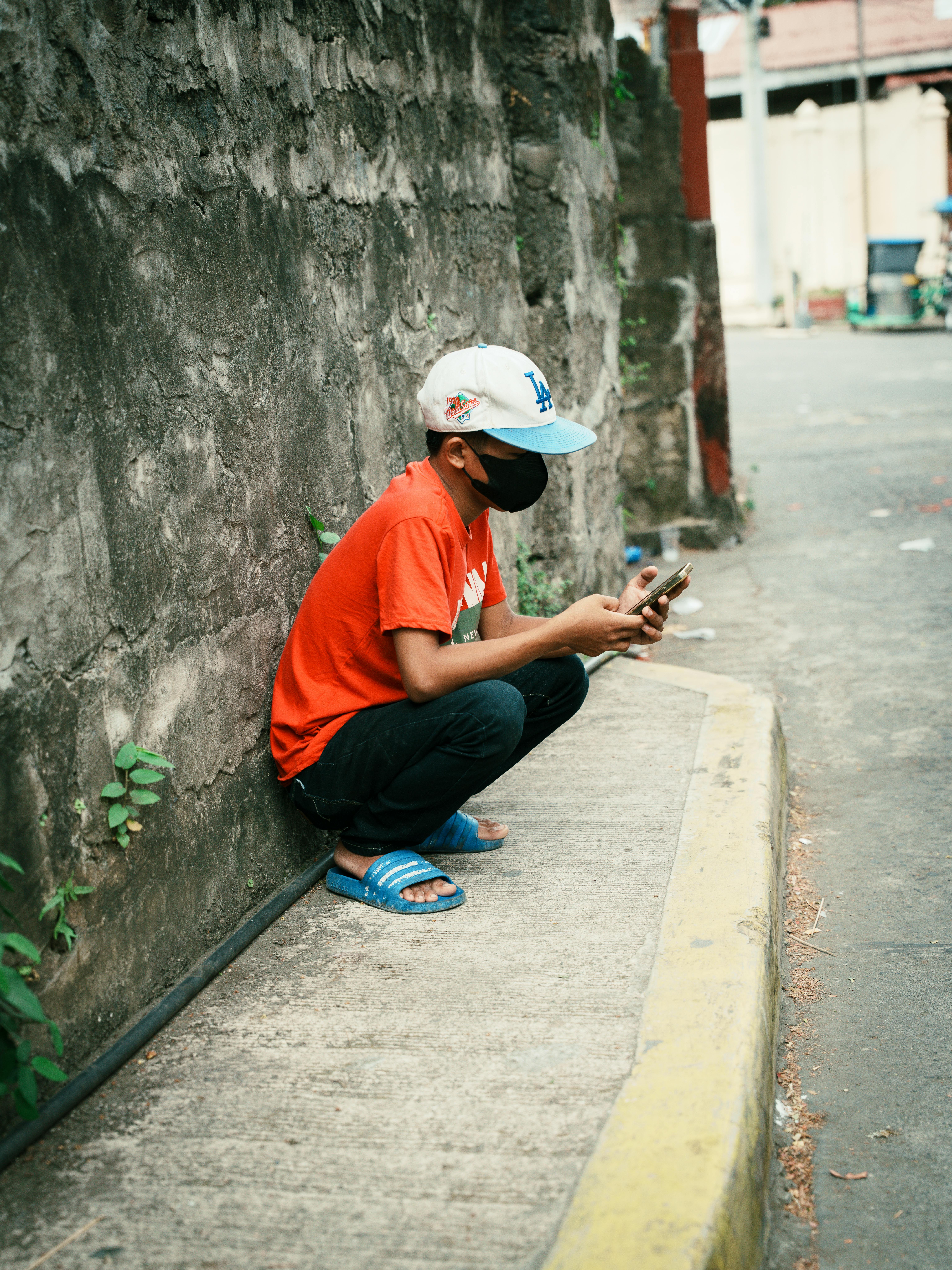 無料 フィリピンのタールの歩道に座り、携帯電話に見入っている若者。 写真素材