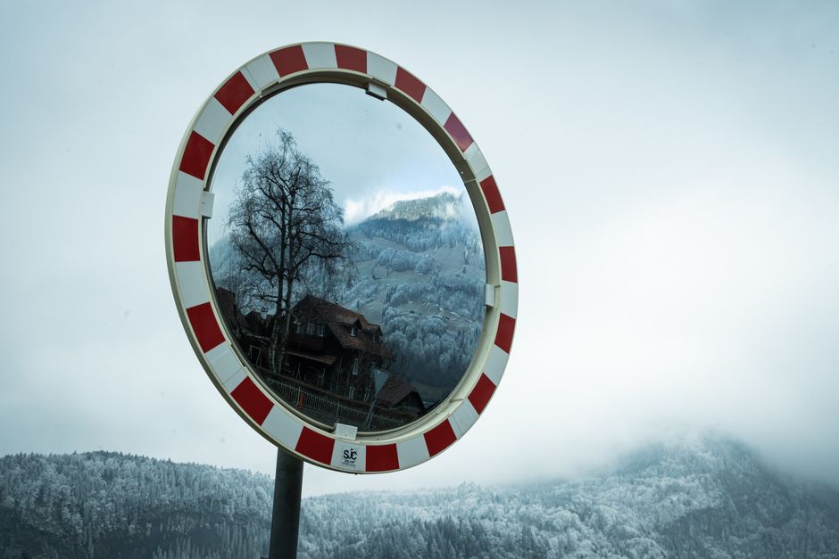 Explore the serene winter landscape mirrored in a road sign in Switzerland.