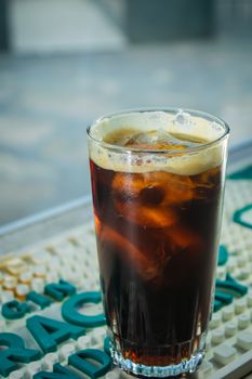 Chilled glass of iced cold brew coffee on a bar mat, perfect for summer refreshment.