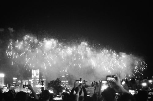 Free A breathtaking fireworks display lights up the night sky above a bustling city skyline, capturing the excitement of celebration. Stock Photo