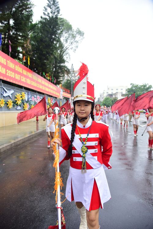 Free Young girl in vibrant band uniform leading a colorful parade in rainy weather. Stock Photo