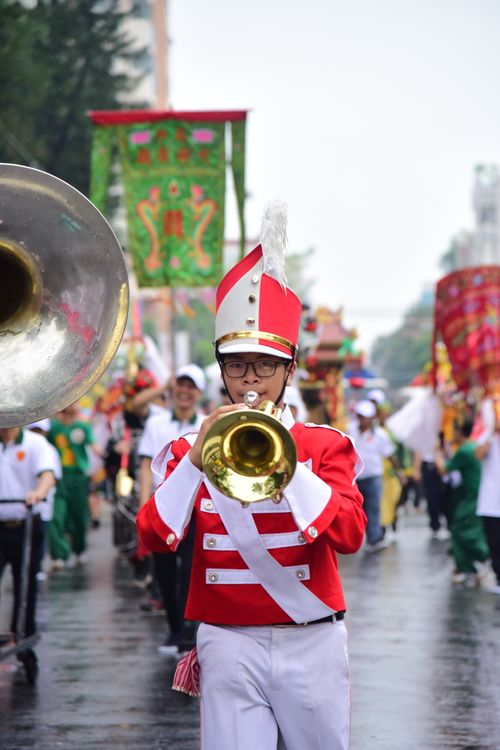 Free Colorful marching band parades through city street, led by trombone player in vivid attire. Stock Photo