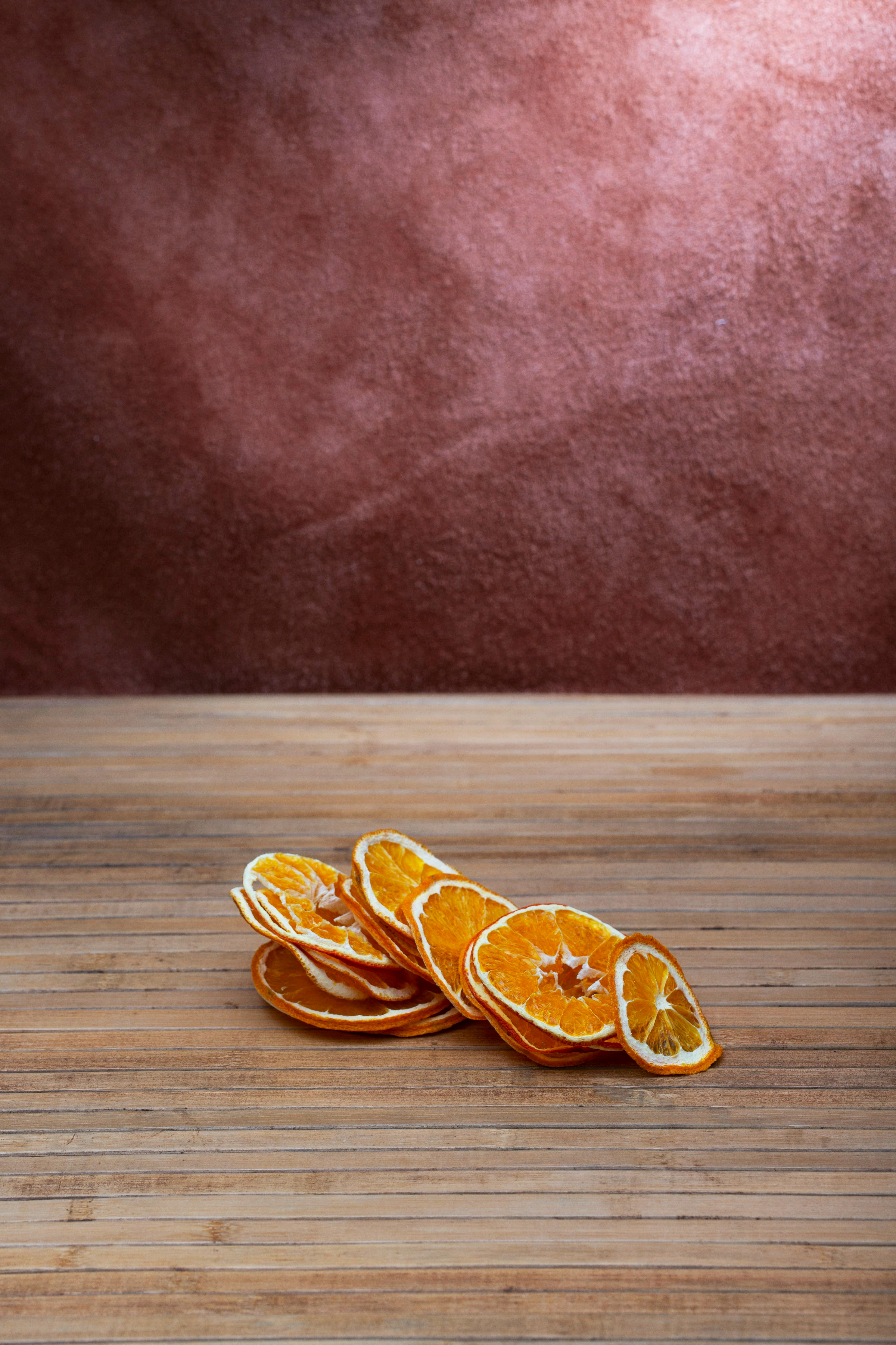 grátis Arranjo elegante de fatias de laranja desidratadas sobre uma superfície de madeira com fundo texturizado marrom. Foto profissional