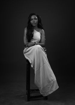 Black and white portrait of a woman posing in a long dress, exuding elegance and grace.