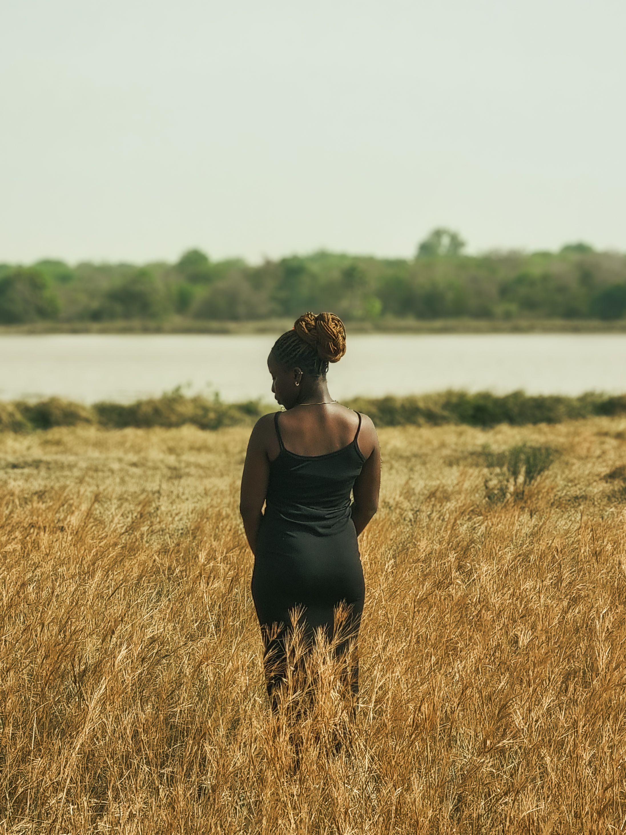 Woman Standing in Field by a River · Free Stock Photo