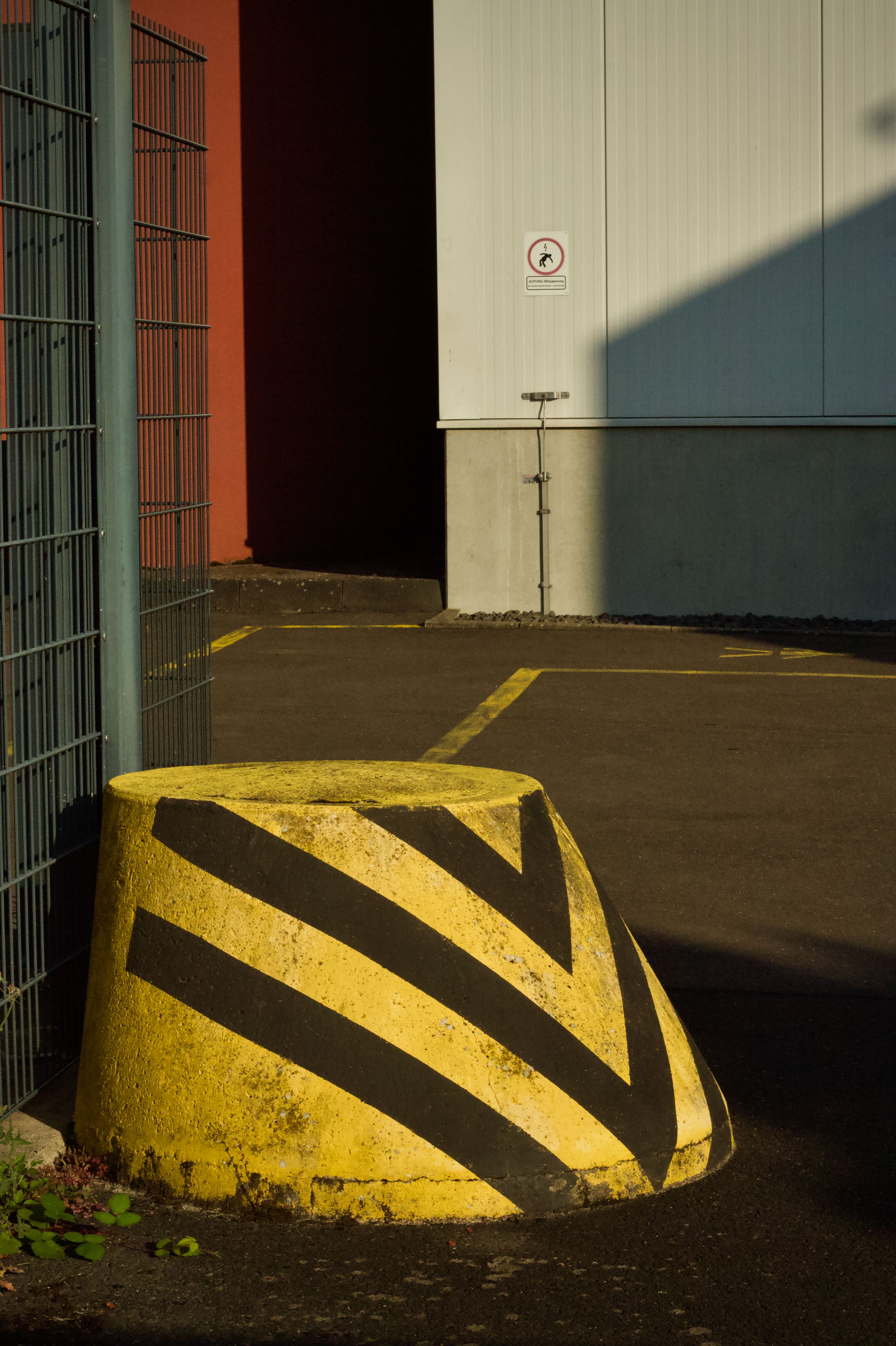 Concrete barrier with yellow and black stripes in industrial area.