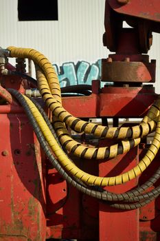 Close-up of red industrial machinery with yellow spiral hoses outdoors.