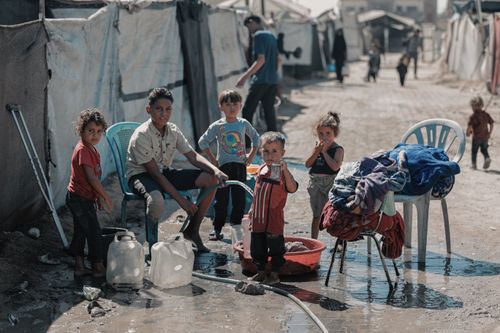 Free Children gathering water in a Gaza refugee camp setting, reflecting daily life. Stock Photo
