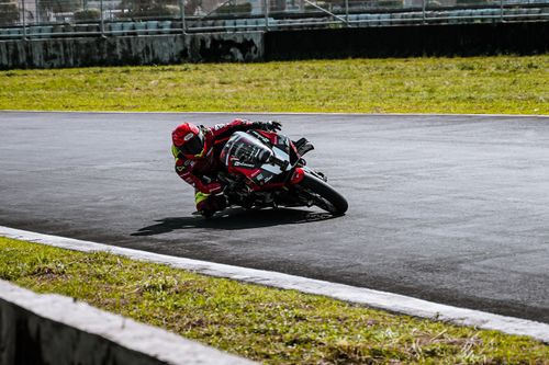 Free A motorcycle racer leans into a curve on a sunny track in Angeles, Philippines. Stock Photo