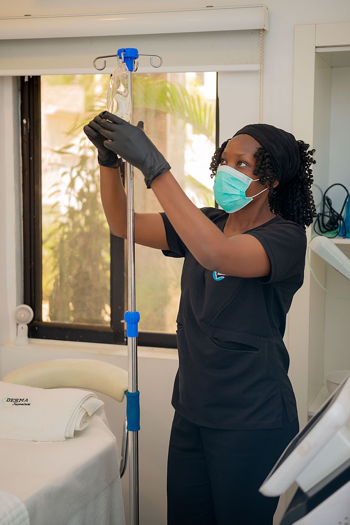 A clinician adjusting an intravenous drip line for a patient in a treatment room, representing supervised NAD+ infusion and injection therapy in Virginia Beach