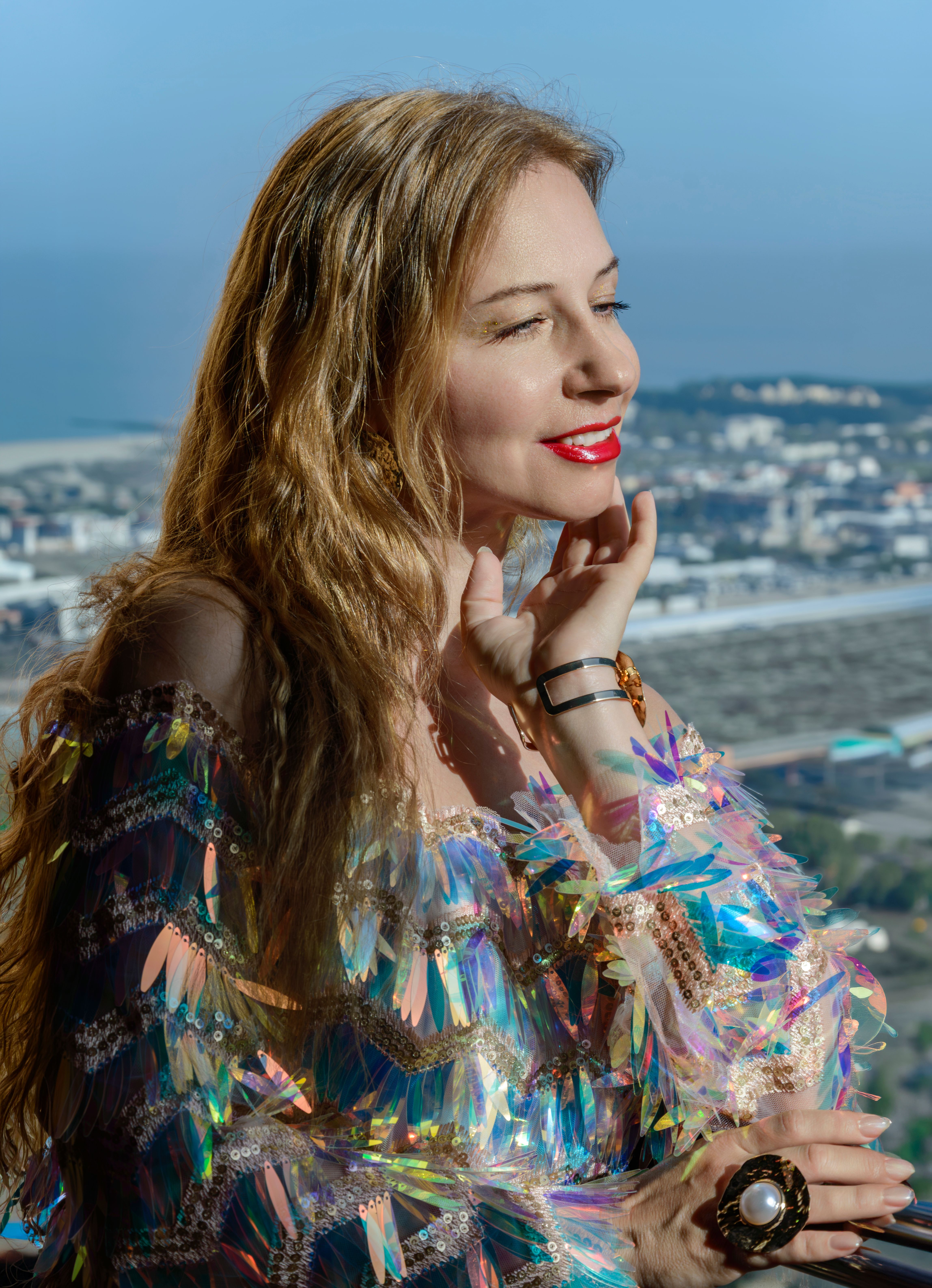 Stylish woman in colorful sequin dress with city view. Perfect for fashion and lifestyle themes.