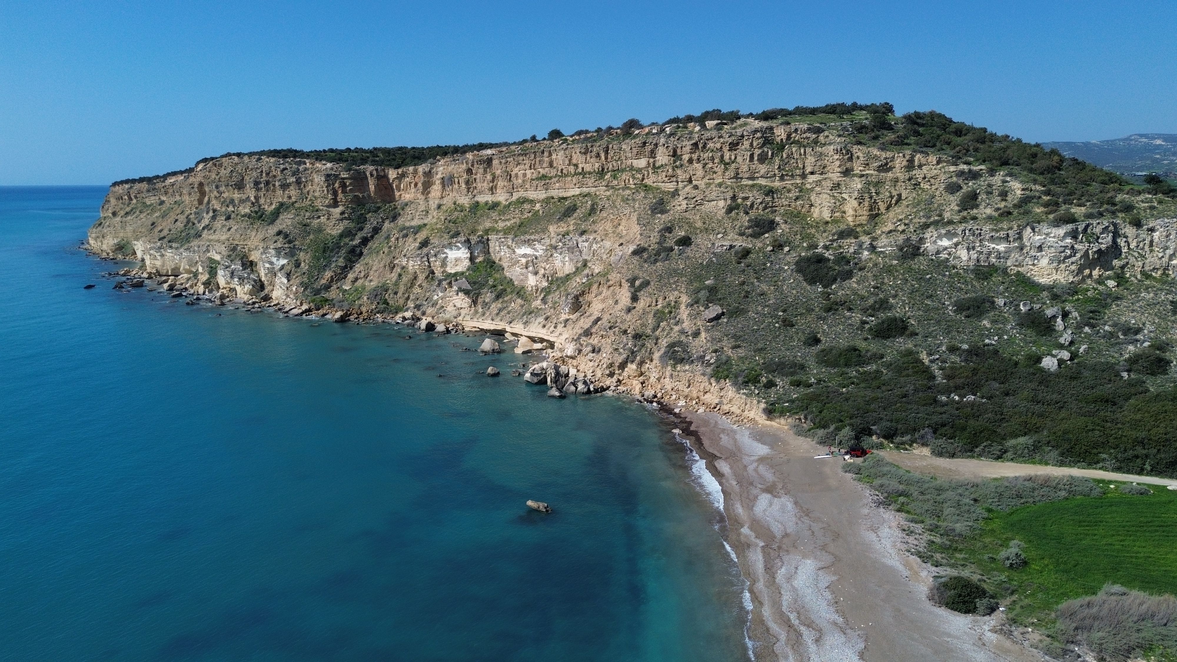 Coastal footpath along white cliffs and sea caves at Cape Greco with deep blue water below