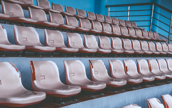 Een rij lege plastic stadionstoelen in een geometrisch patroon, die een levendige blauwe sfeer uitstralen.