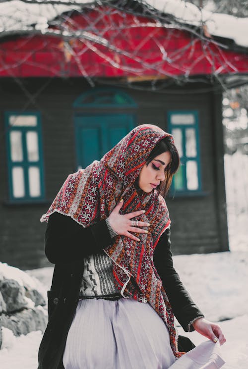 Woman in Red and White Scarf Standing on Snow Covered Ground