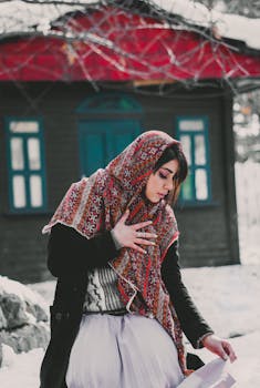 冬天，一名妇女在小屋前戴着一条色彩缤纷的传统围巾