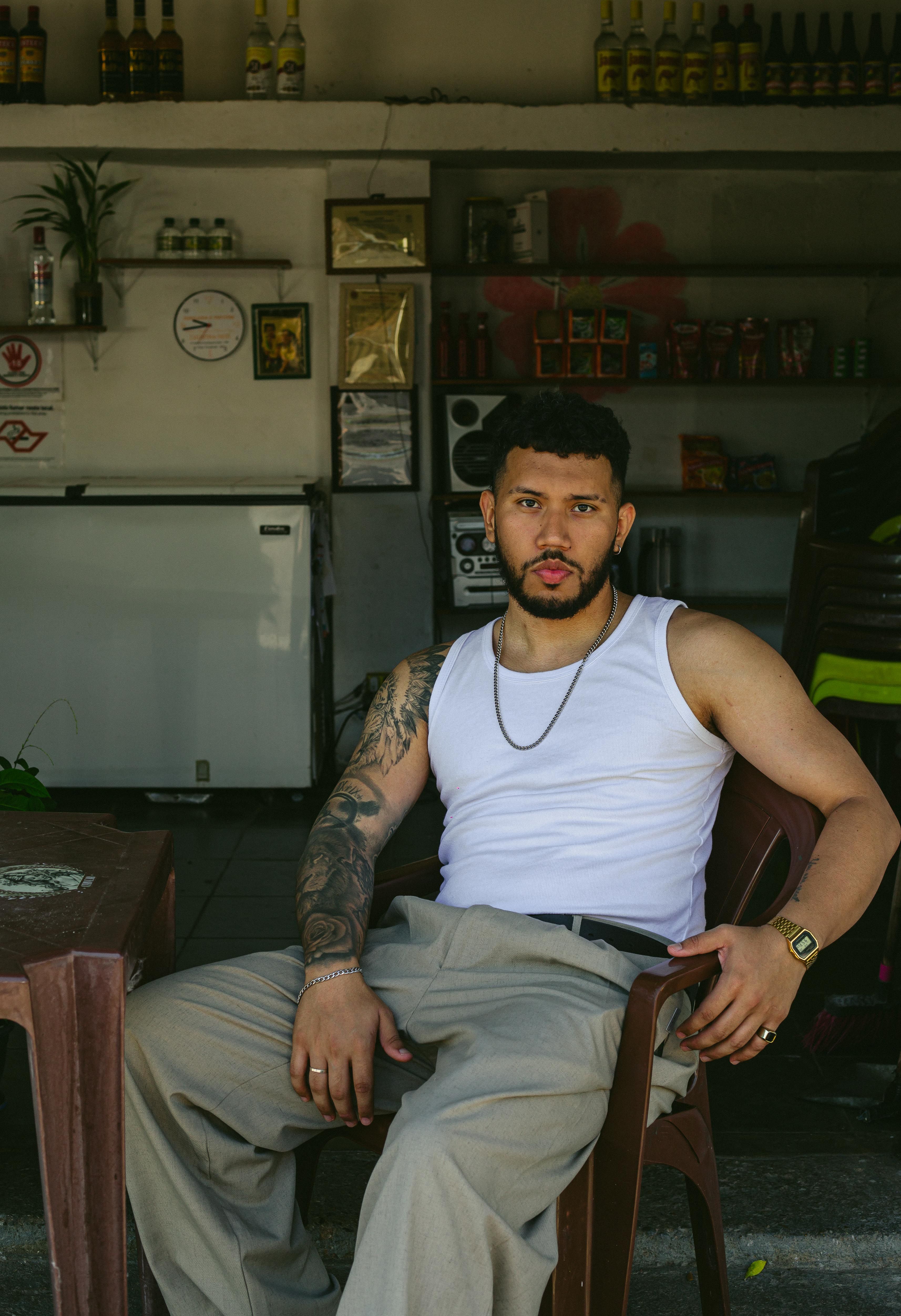 Portrait of a stylish man with tattoos and curly hair at an outdoor bar in Presidente Prudente, Brazil.