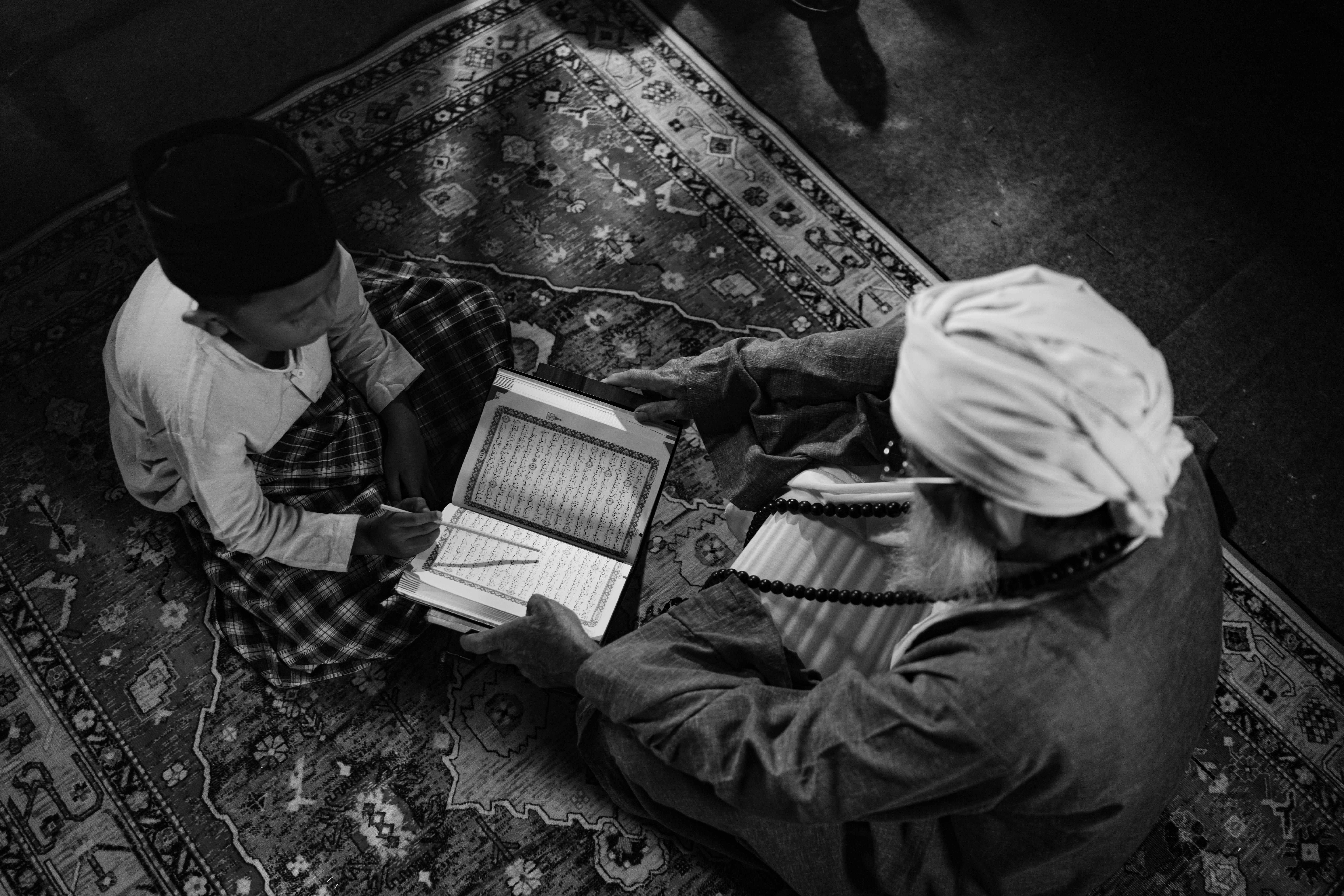 Gratis Immagine in bianco e nero di un ragazzo che impara da un anziano, che mette in risalto l'educazione islamica tradizionale a Giacarta. Foto a disposizione
