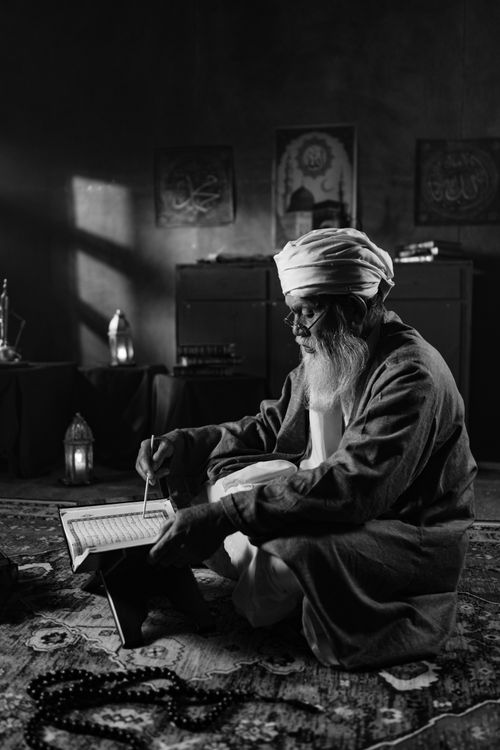 Free Black and white image of an elderly man reading a religious book in an indoor setting, creating a serene atmosphere. Stock Photo