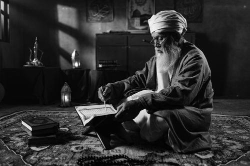 Free Black and white photo of an elderly man reading a religious book indoors, evoking serenity. Stock Photo