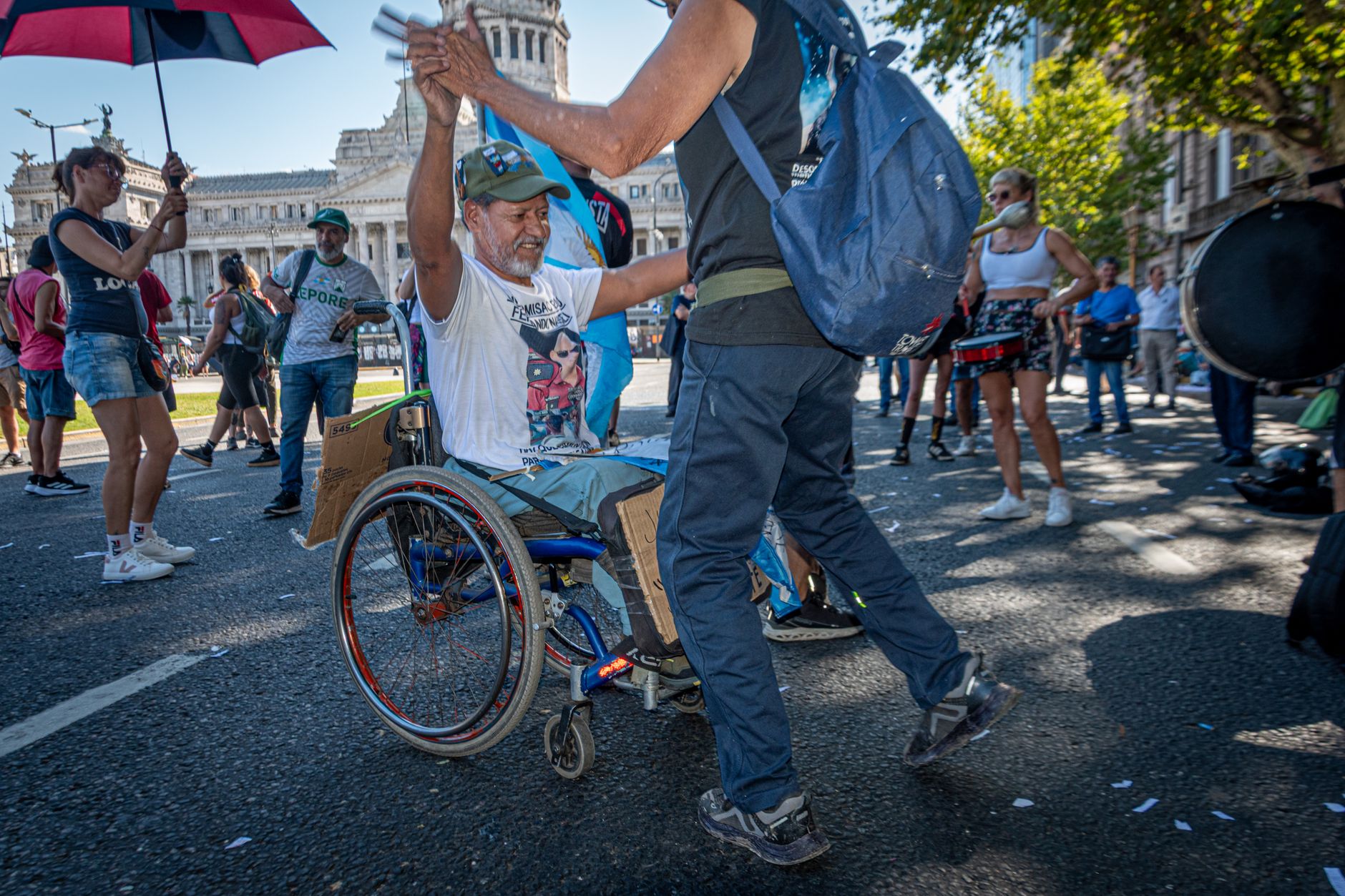 Joyful street dancing protest in Buenos Aires, featuring diverse people participating, one in a wheelchair.