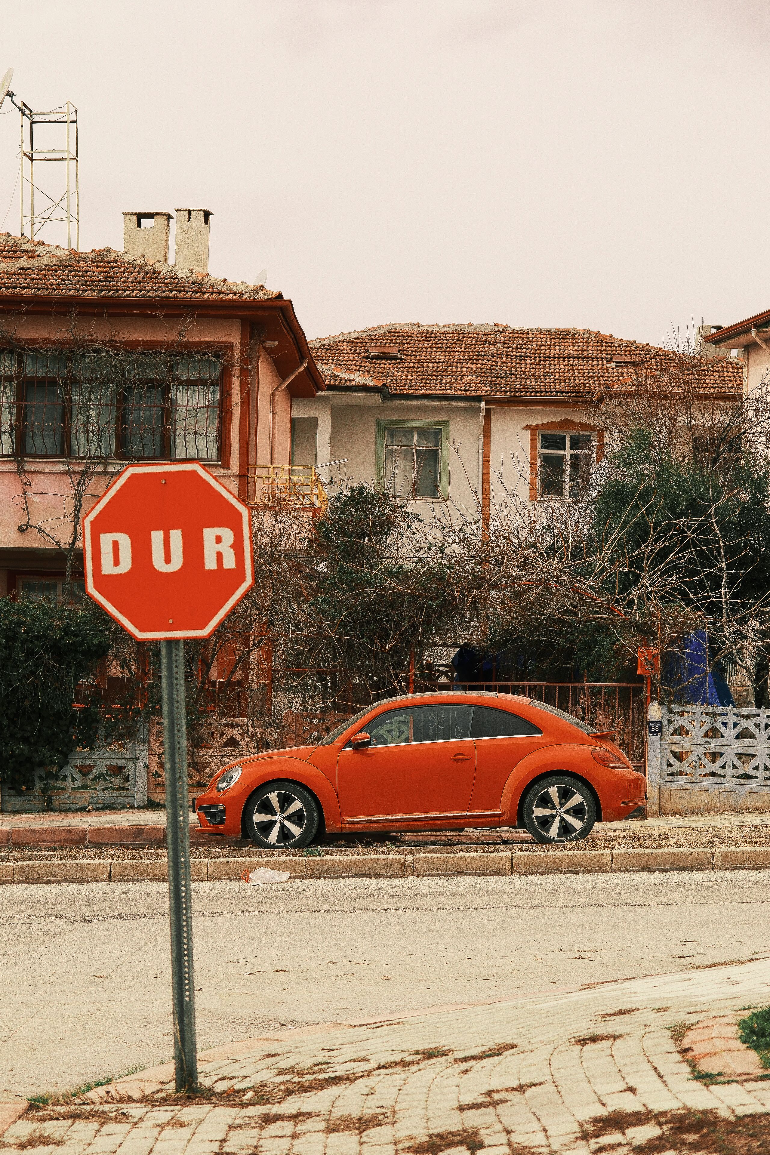 Orange Car Parked by Stop Sign in Suburban Street · Free Stock Photo