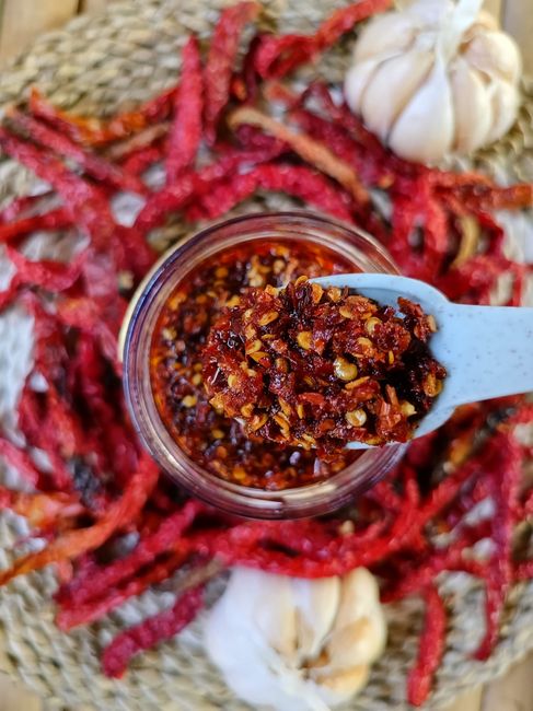 red chili oil in glass jar with spoon