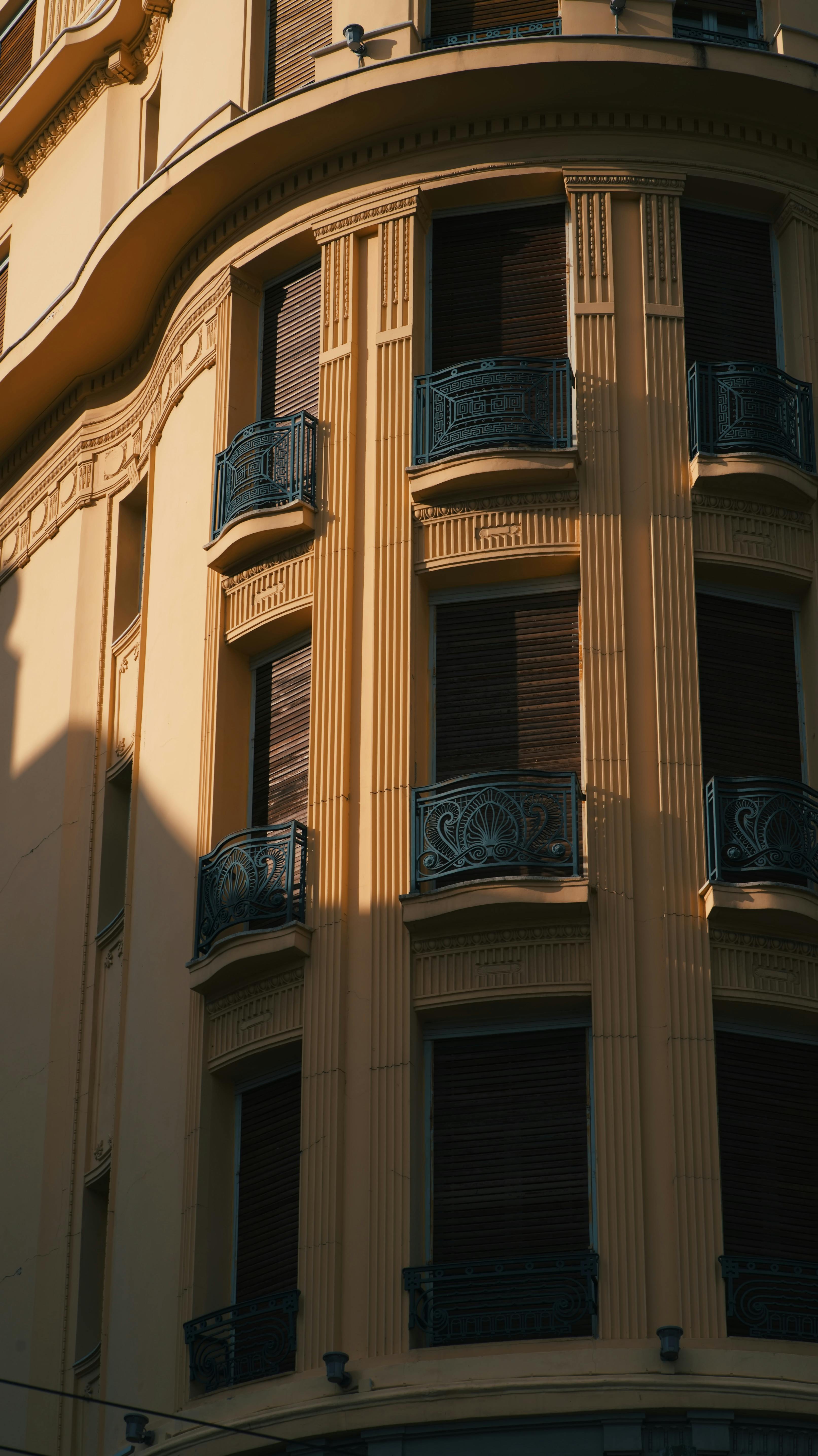 grátis Fachada elegante de um prédio da cidade com varandas de ferro ornamentadas, capturada sob a luz quente do dia. Foto profissional
