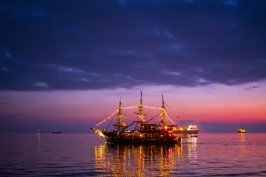 Beautifully lit ship on calm waters during a vibrant sunset, perfect for travel themes.