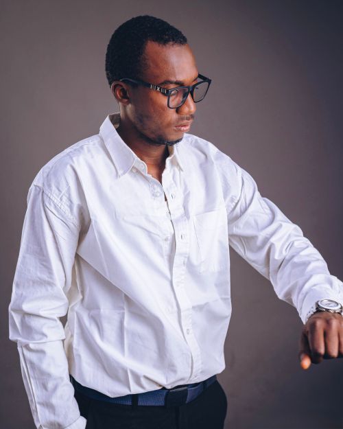 Free Portrait of a man in a white shirt and glasses checking time indoors. Stock Photo