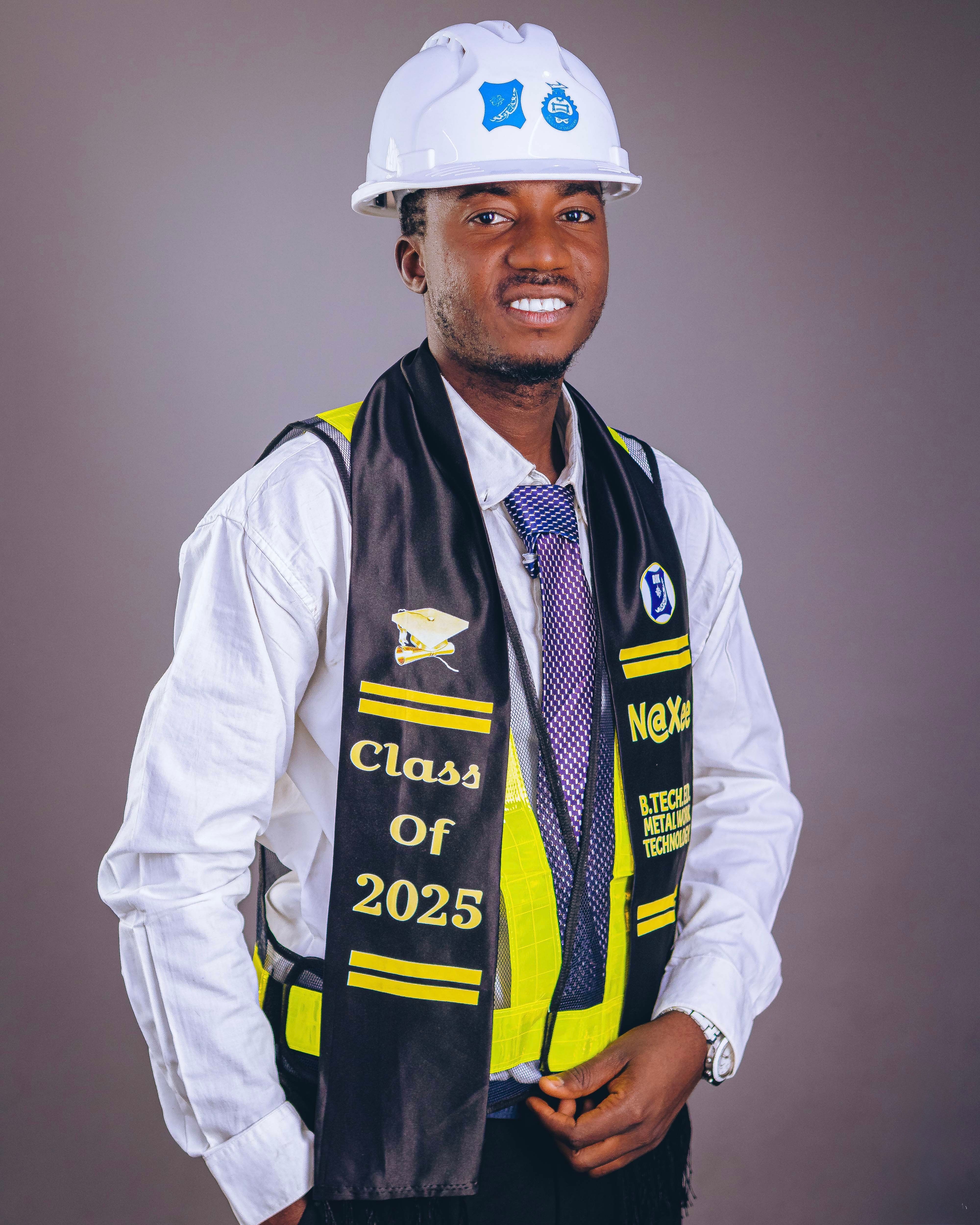 Confident young engineer wearing a hard hat and graduation stole celebrating academic achievement.