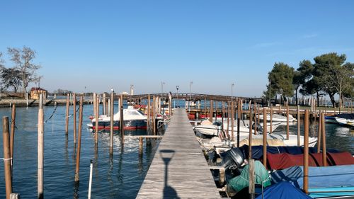 Free Scenic view of a wooden dock with boats in a sunny Venetian harbor. Stock Photo
