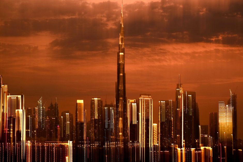 Stunning view of Dubai skyline with the iconic Burj Khalifa at sunset, reflecting vibrant city lights.