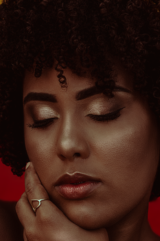 Elegant closeup of a woman with curly hair and makeup, against a red background.