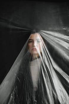 这幅引人注目的女性肖像描绘了一位被塑料遮住的女性，突出了污染与女权主义的主题