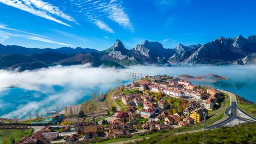Free Captivating aerial view of Riaño, Spain with mist over the mountains and vibrant village colors. Stock Photo