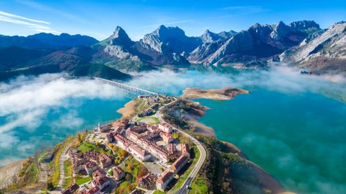 Free Stunning aerial view of Riaño with the Cantabrian Mountains and a scenic lake. Stock Photo
