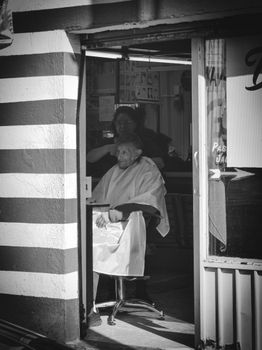 Black and white photo capturing a senior man in a traditional barber shop in Toluca de Lerdo, Mexico.