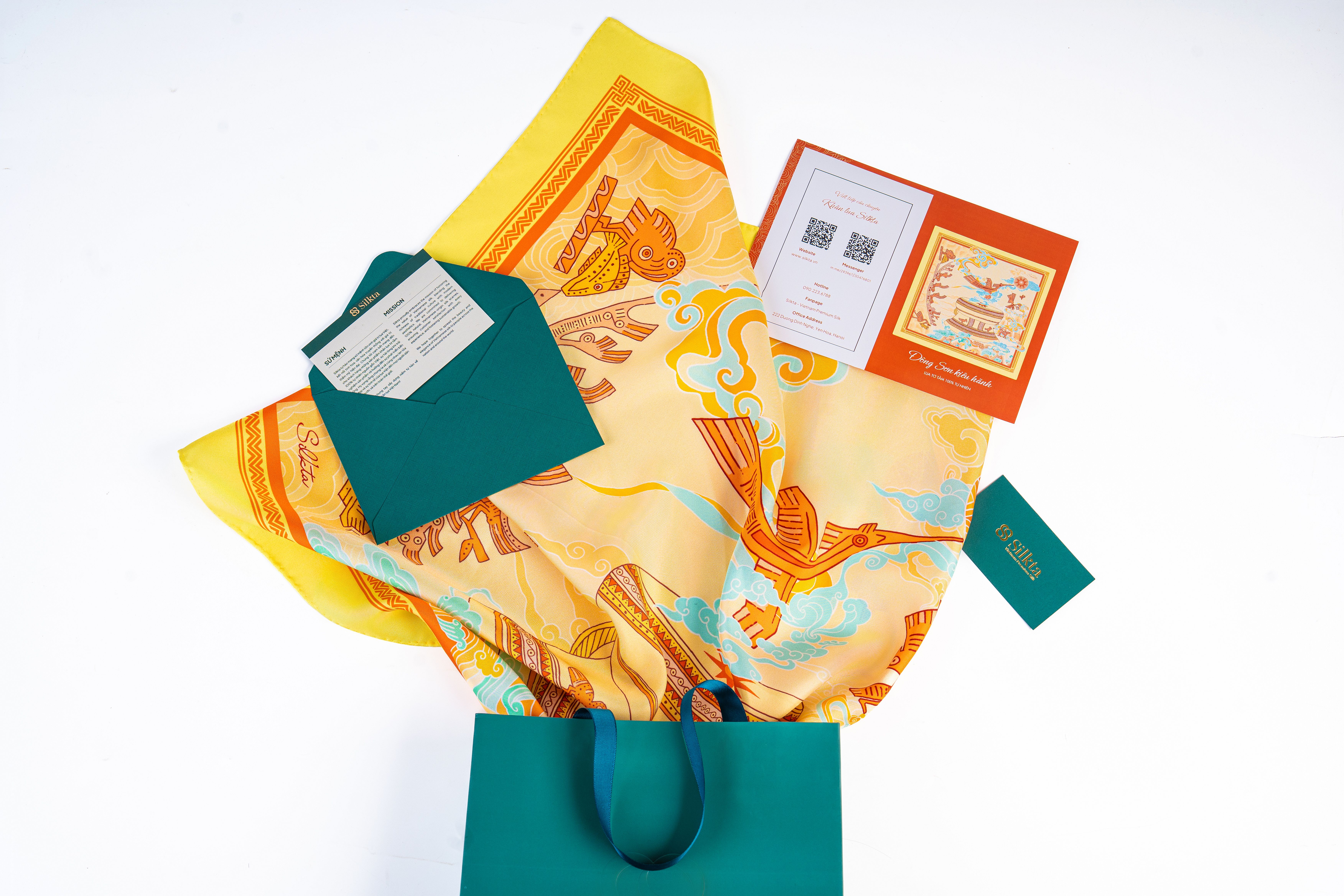 Colorful silk scarf displayed with gift packaging and cards, artistic design.
