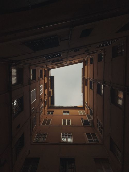 Free View from a narrow courtyard looking upwards towards the sky, creating a dramatic visual perspective. Stock Photo
