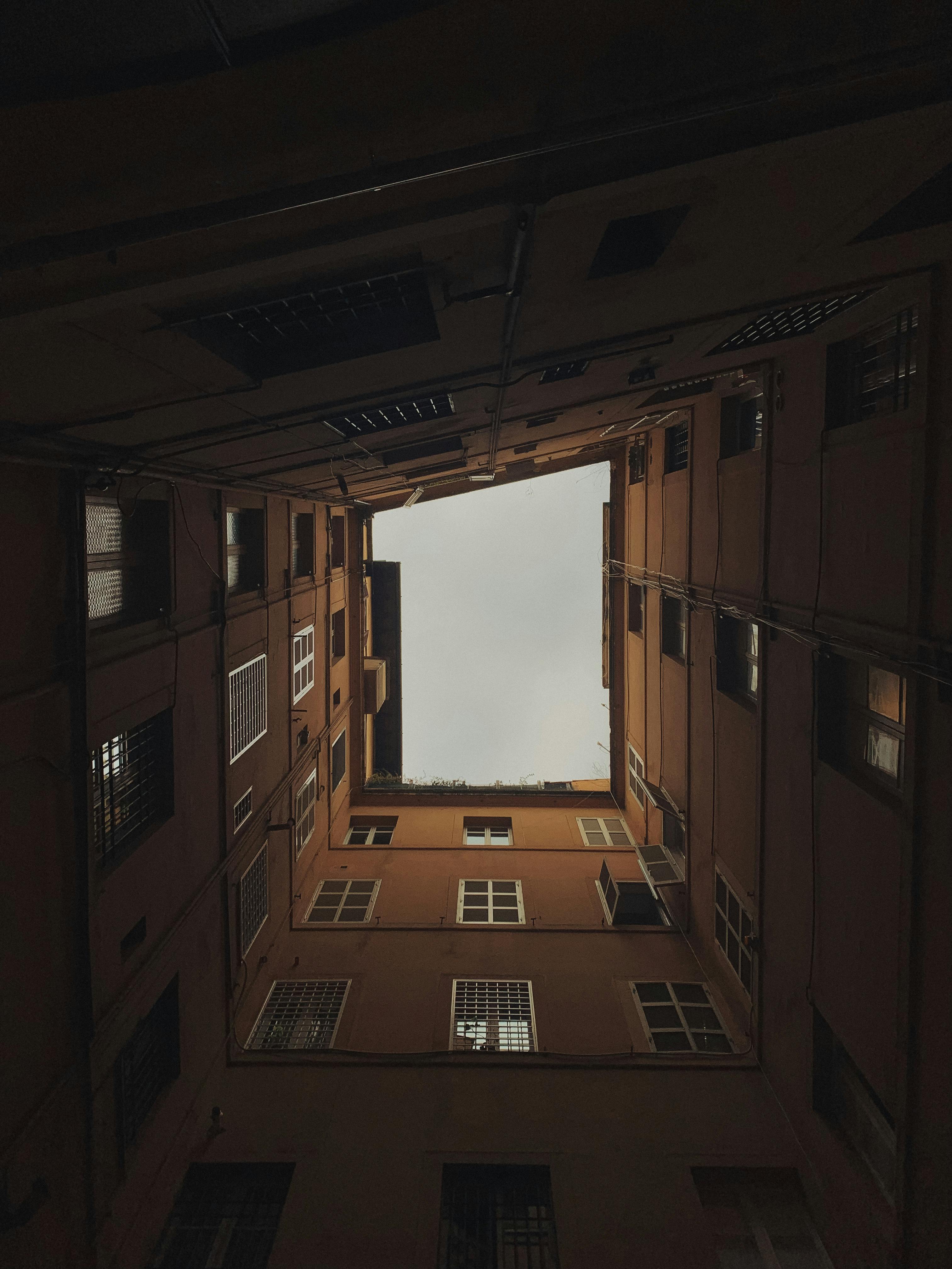 Kostnadsfria Utsikt från en smal innergård uppåt mot himlen, vilket skapar ett dramatiskt visuellt perspektiv. Stock foto