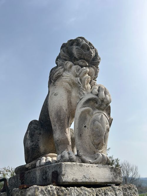 Free A stone lion statue sits majestically outdoors against a clear blue sky. Stock Photo