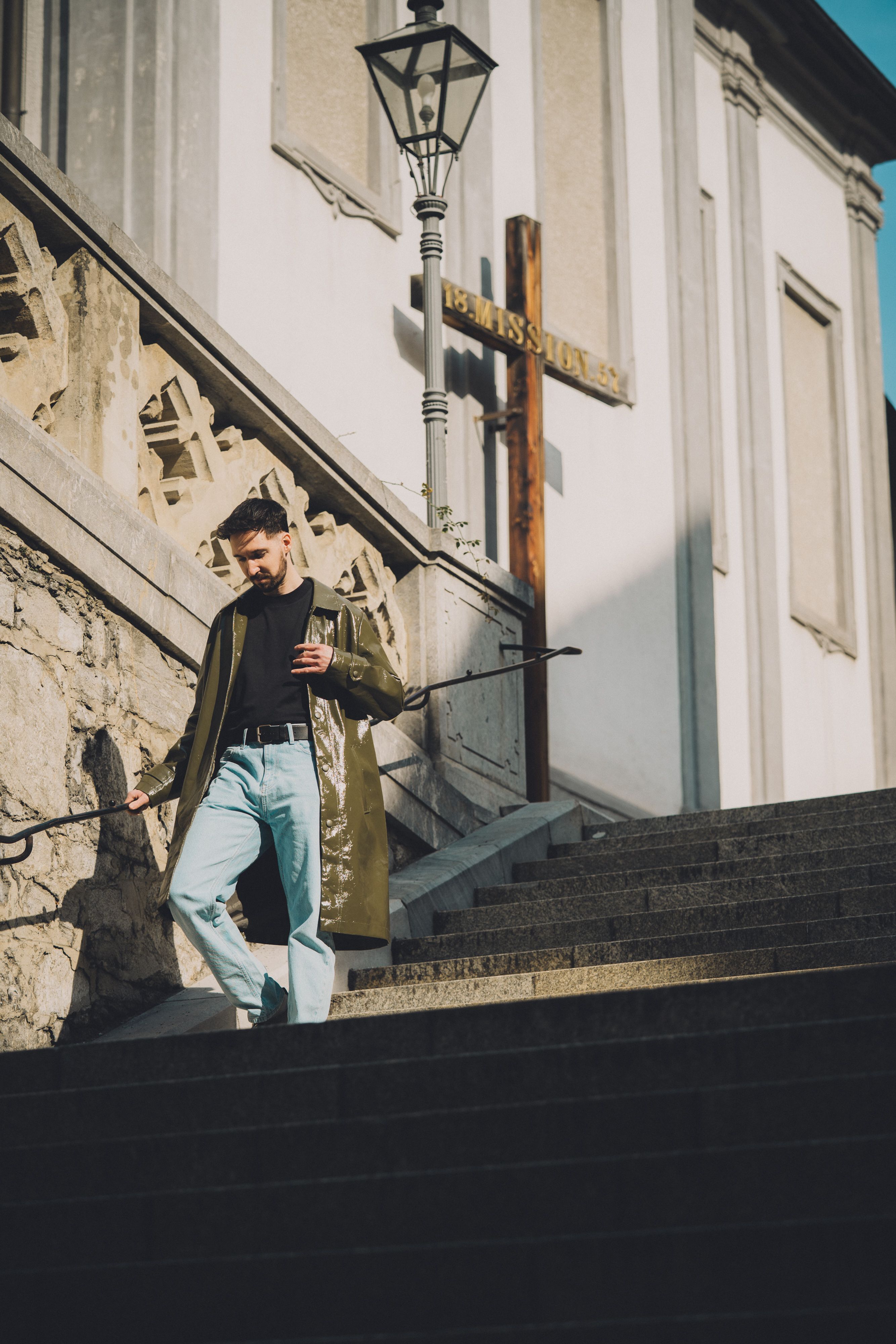 A young man descends historic steps in Graz, exhibiting modern urban fashion in a casual outdoor setting.