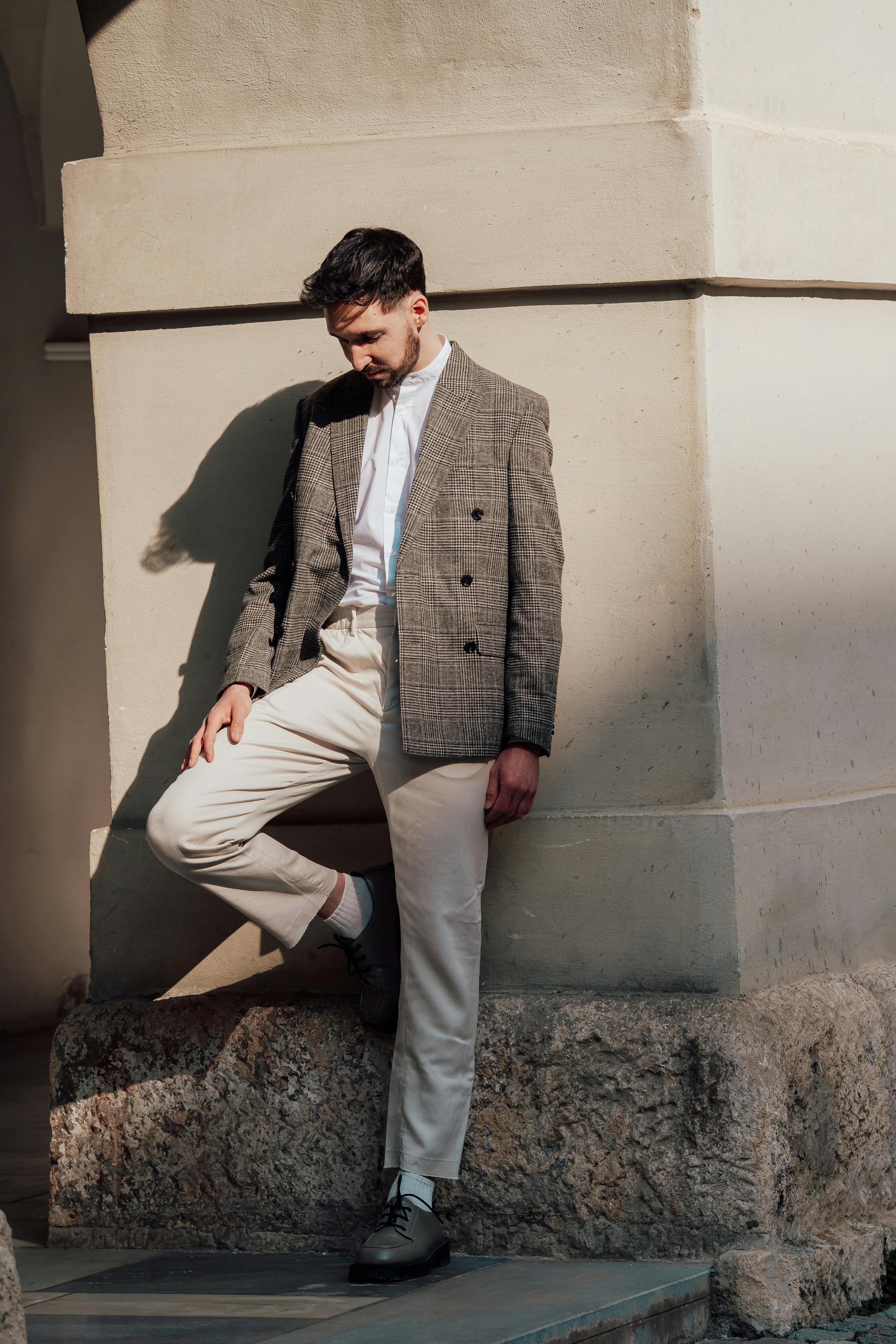 Portrait of a fashionable man in sunlight, leaning against a wall in Graz, Austria.
