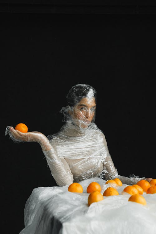 Woman in White Long Sleeve Shirt Holding Orange Fruit