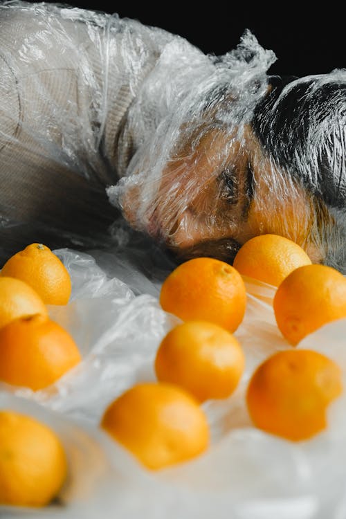 Апельсиновые фрукты перед женщиной, покрытой пластиком