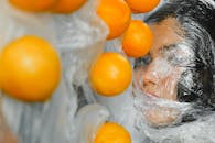 一幅描绘妇女用塑料包裹橙子的艺术肖像，突出了污染与生态问题