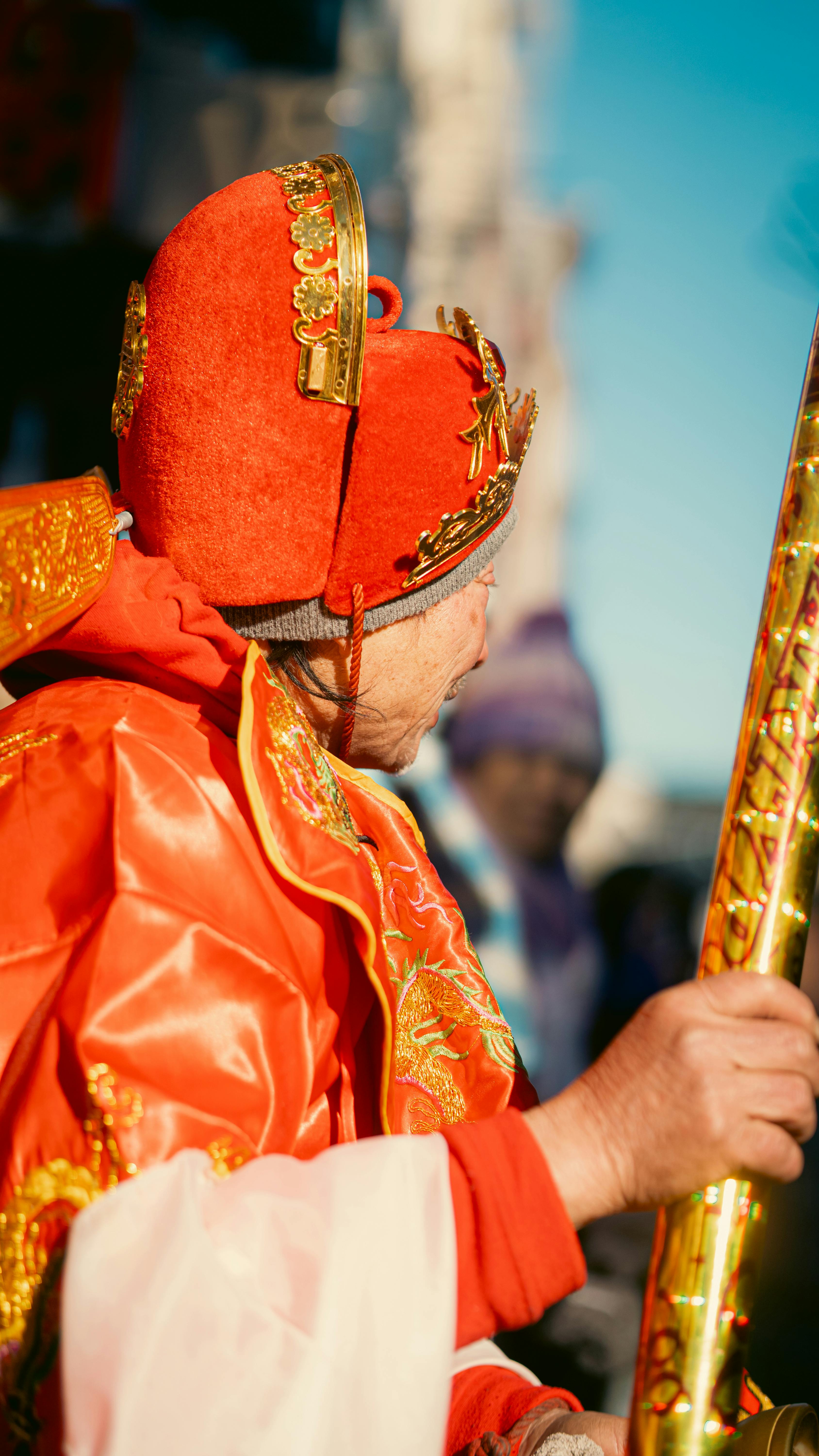 An adult in colorful traditional attire celebrates outdoors in vibrant cultural attire, New York.