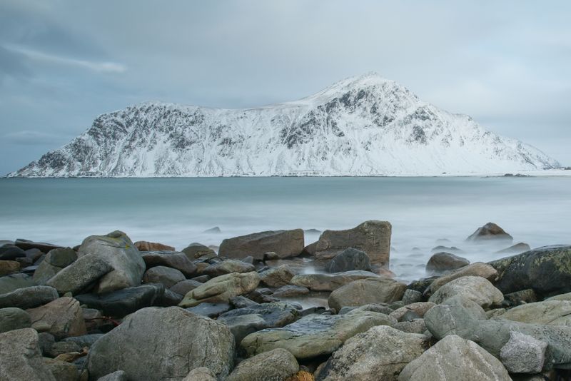 A snowy mountain above a rocky winter shoreline — photo by Miluse Weberova on Pexels