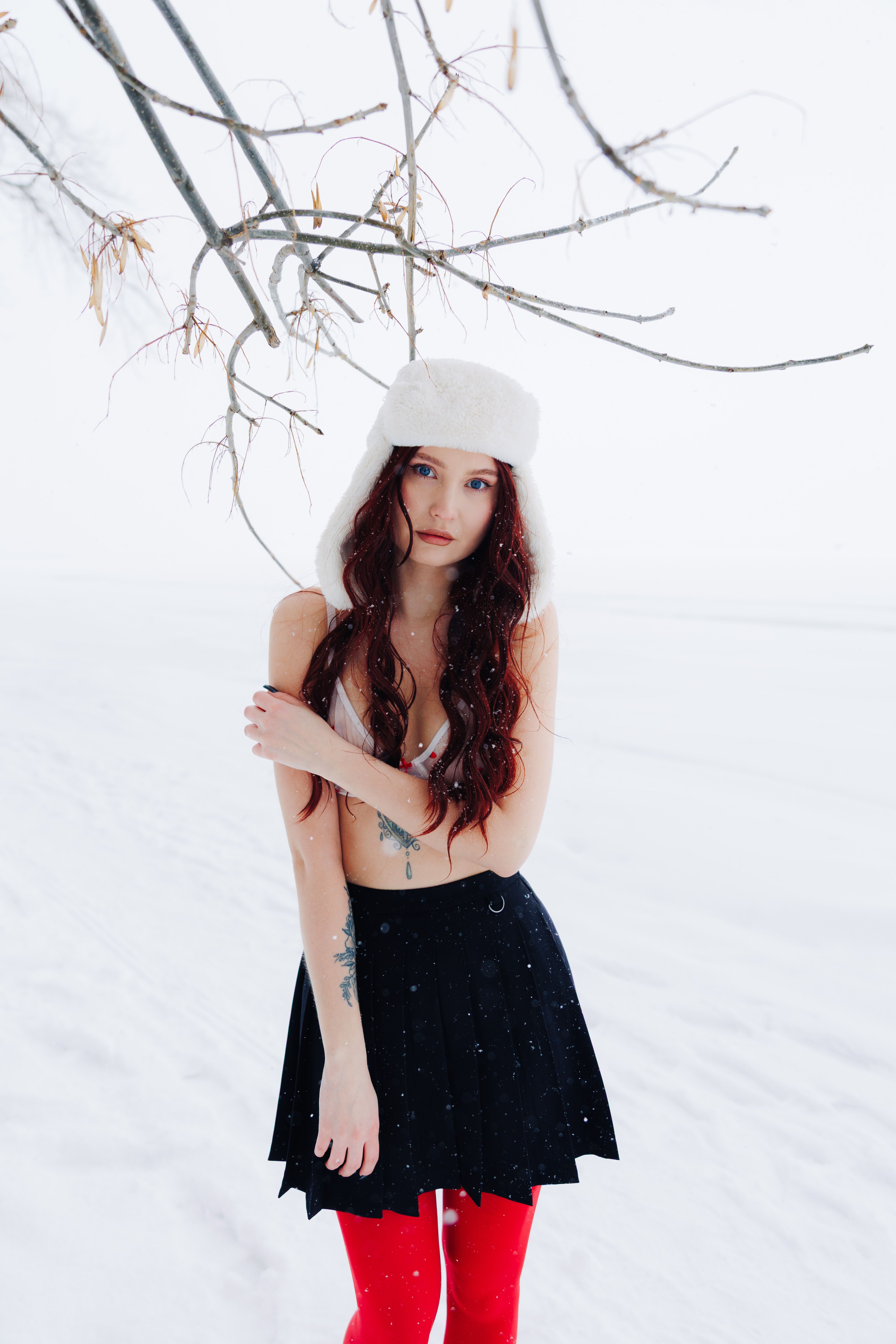 Young woman in winter attire standing in a snowy landscape, showcasing fashion in nature.